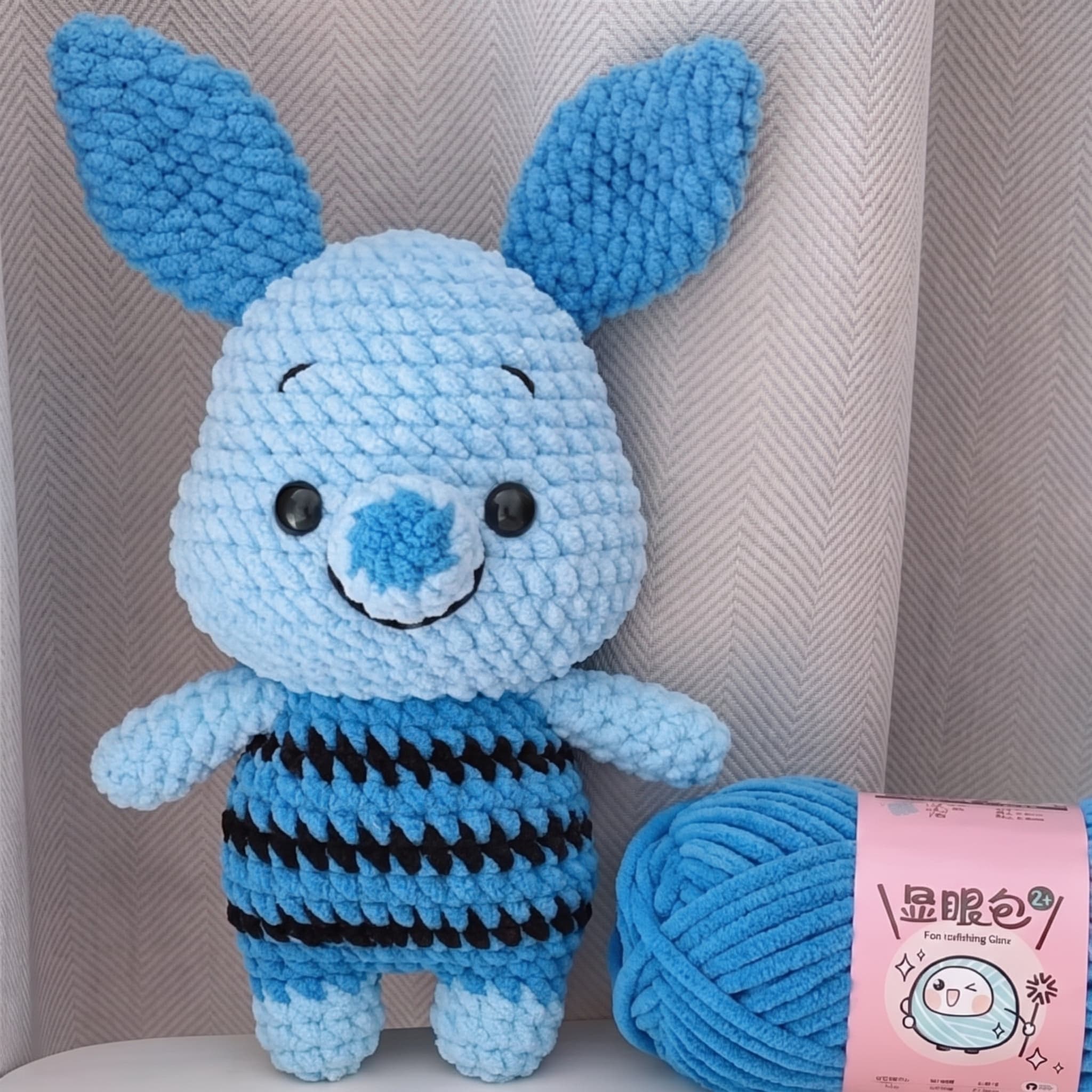 Blue plush crochet bunny amigurumi with long floppy ears and a black-striped tummy