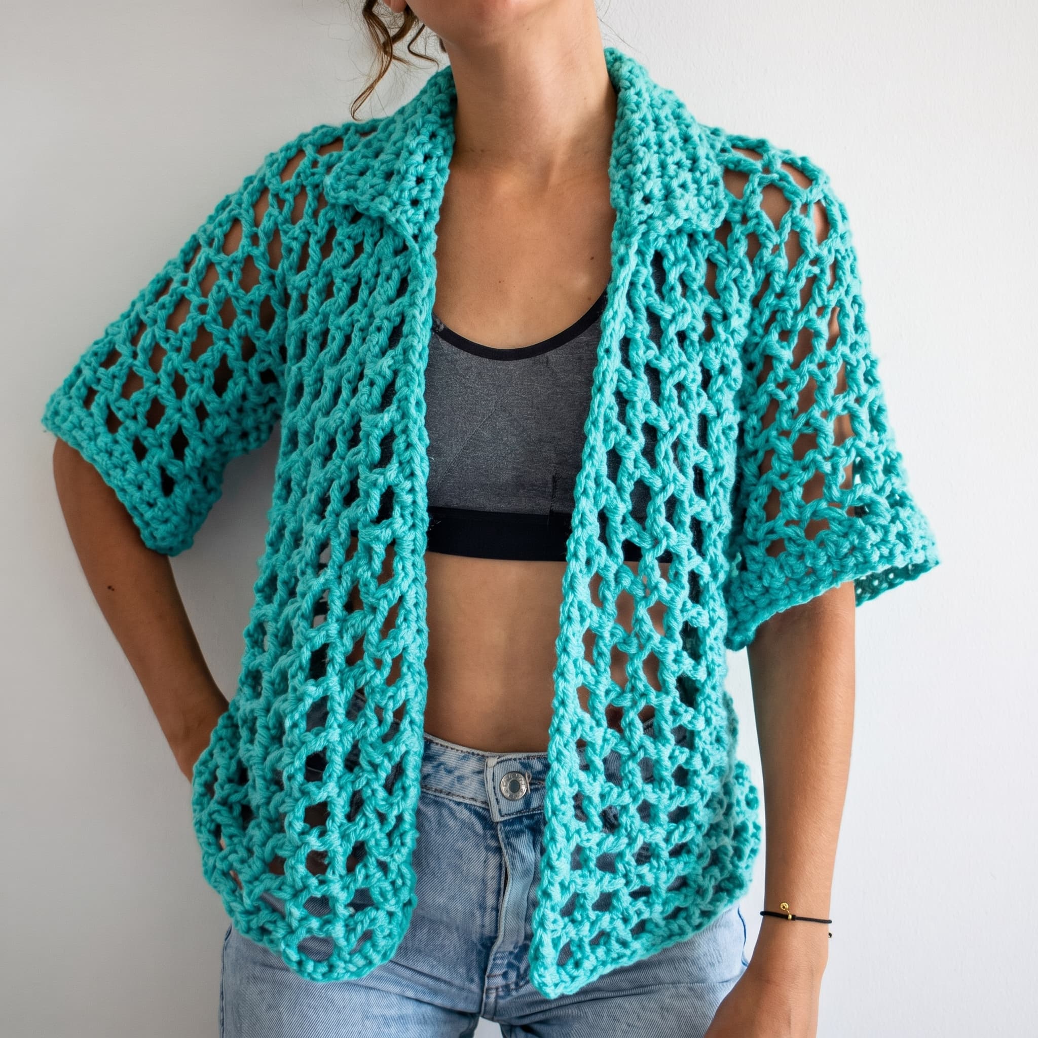 Teal open-mesh crochet overshirt worn open over a grey top and jeans