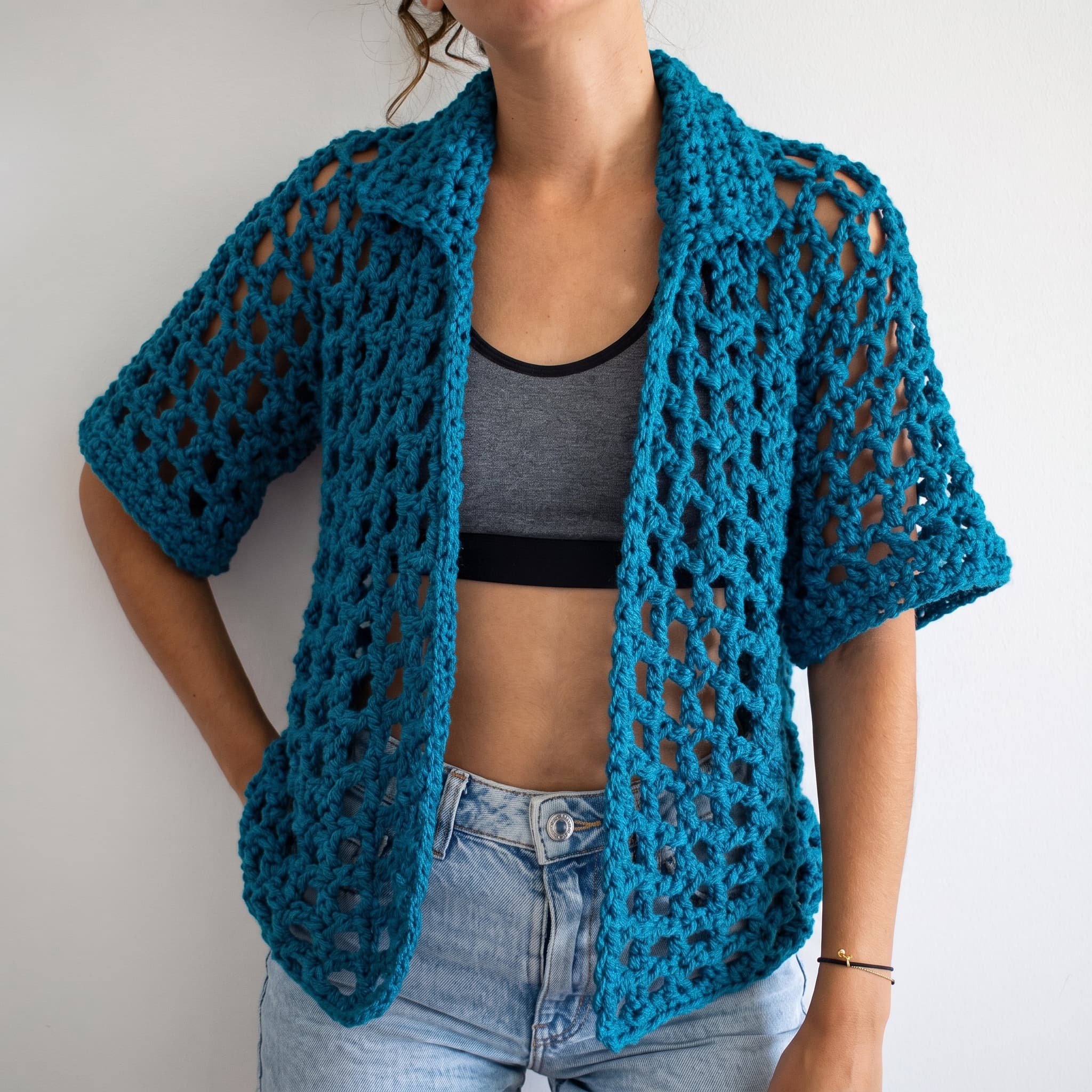 Deep teal open-mesh crochet overshirt worn over a grey crop top