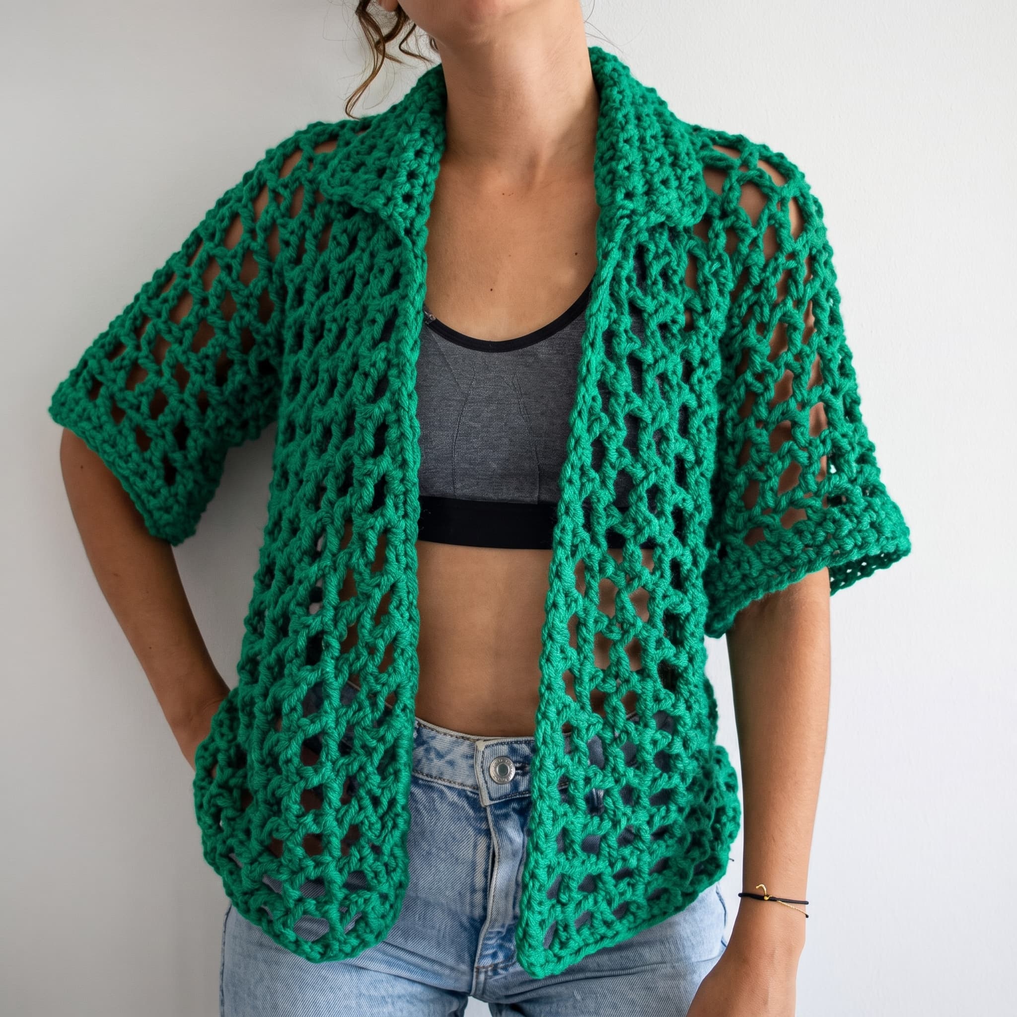 Green open-mesh crochet overshirt worn open over a grey top and jeans