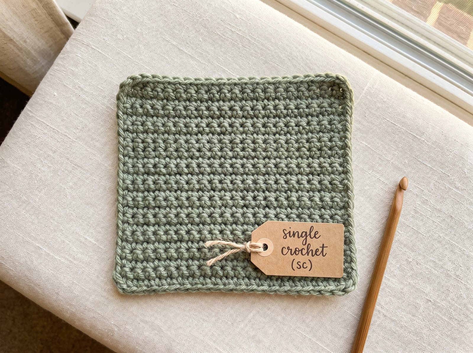 A finished single crochet swatch in sage yarn labeled "single crochet."