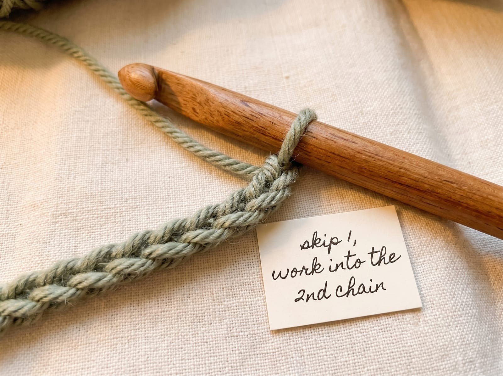 Crochet hook inserted into the second chain of a foundation chain to begin the first row of single crochet.