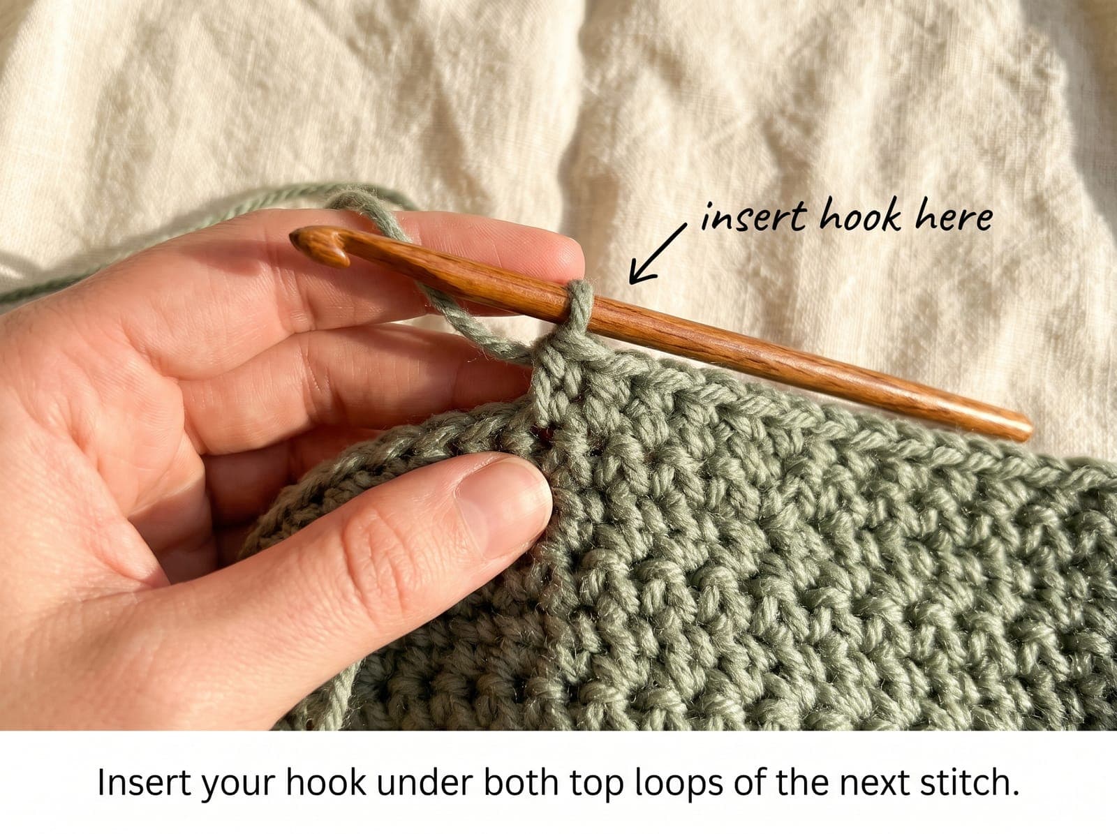 Crochet hook being inserted under the top two loops of a stitch.