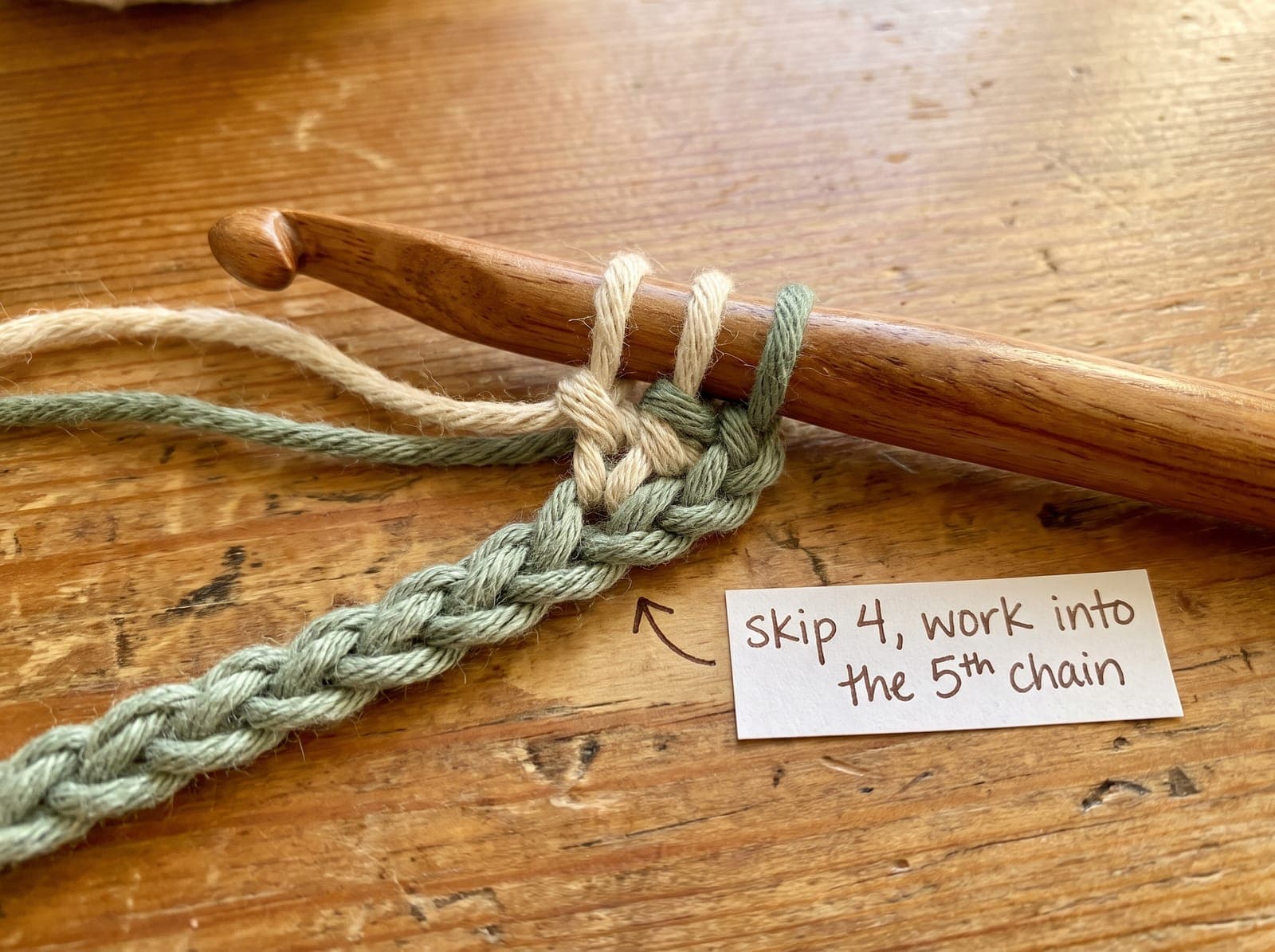 Crochet hook inserted into the fifth chain of a foundation chain to begin the first row of treble crochet.