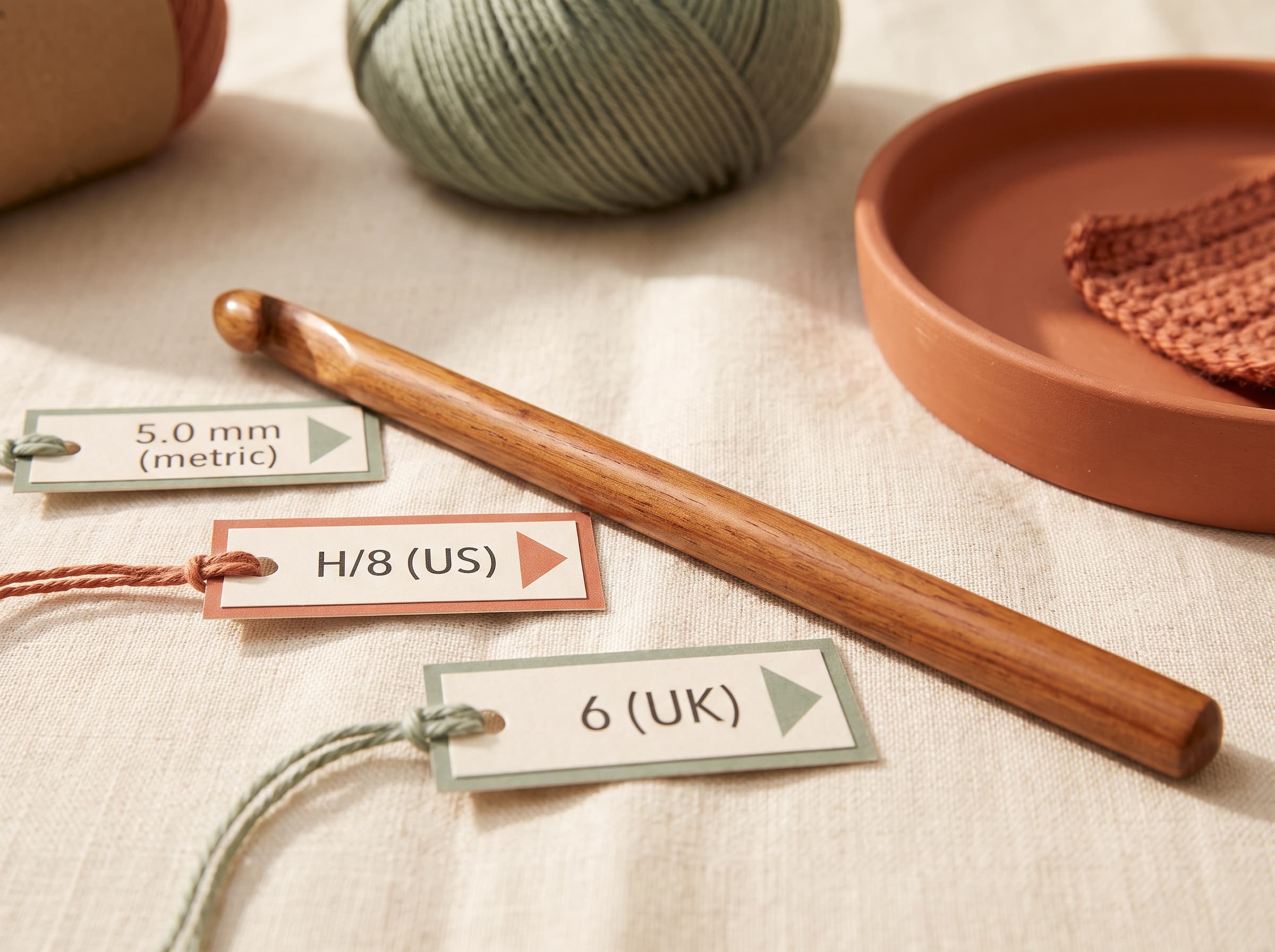 One crochet hook labeled with its three size names: 5.0mm metric, H/8 US, and 6 UK.