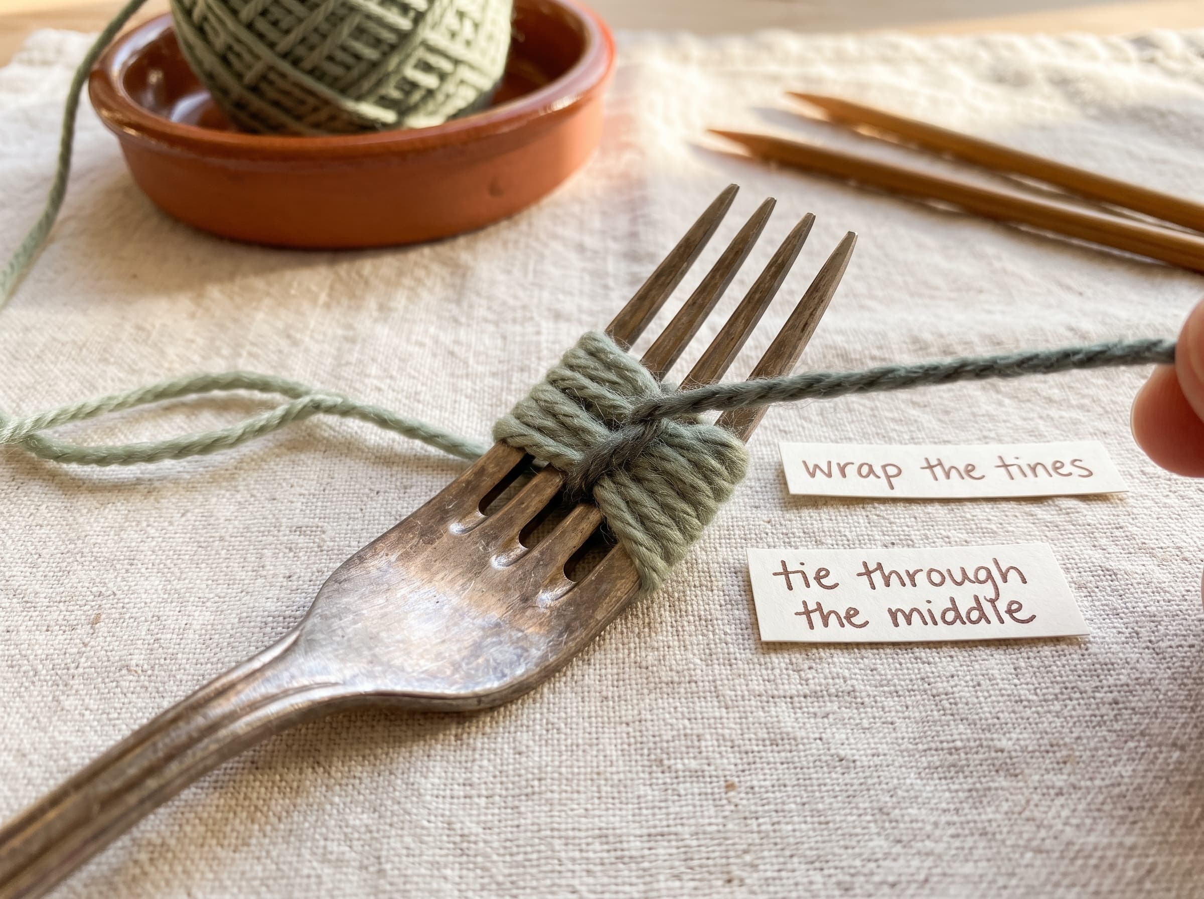 Making a small pom pom with a fork: yarn wrapped around the tines and tied tightly through the center.