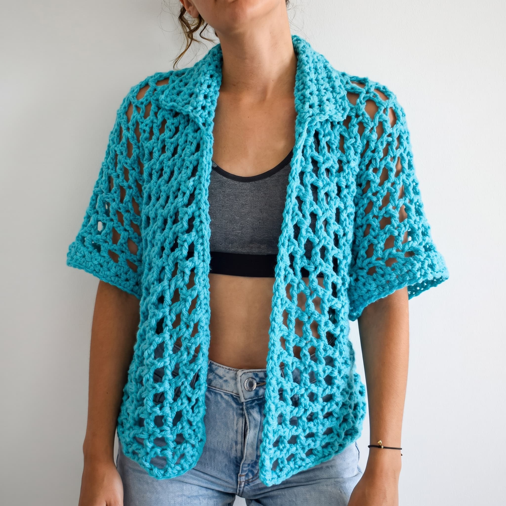 Turquoise open-mesh crochet overshirt with a collar worn over a grey top
